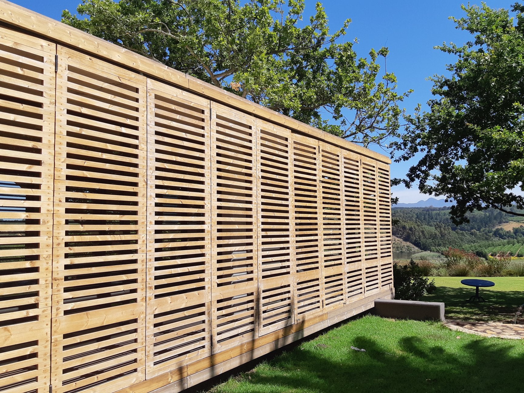 Wooden privacy screen with trees and a clear blue sky in the background