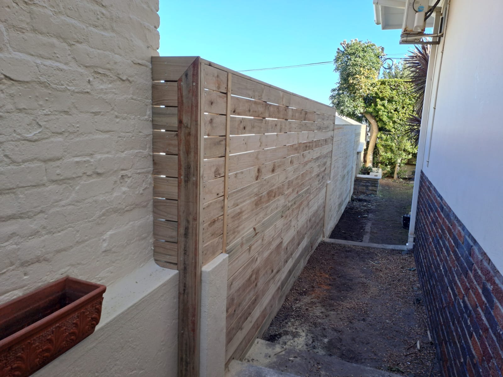 Wooden privacy fence against a white wall.